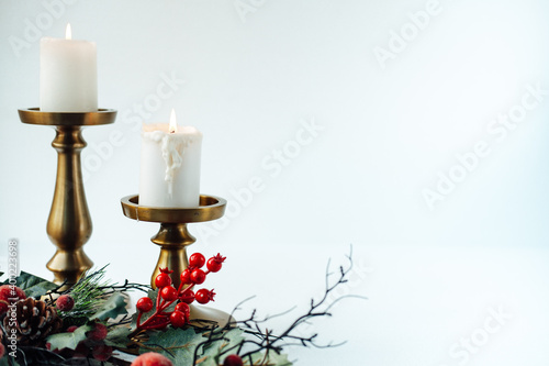 gold candlesticks and candles on a white background. christmas branch with berries . serving the festive table