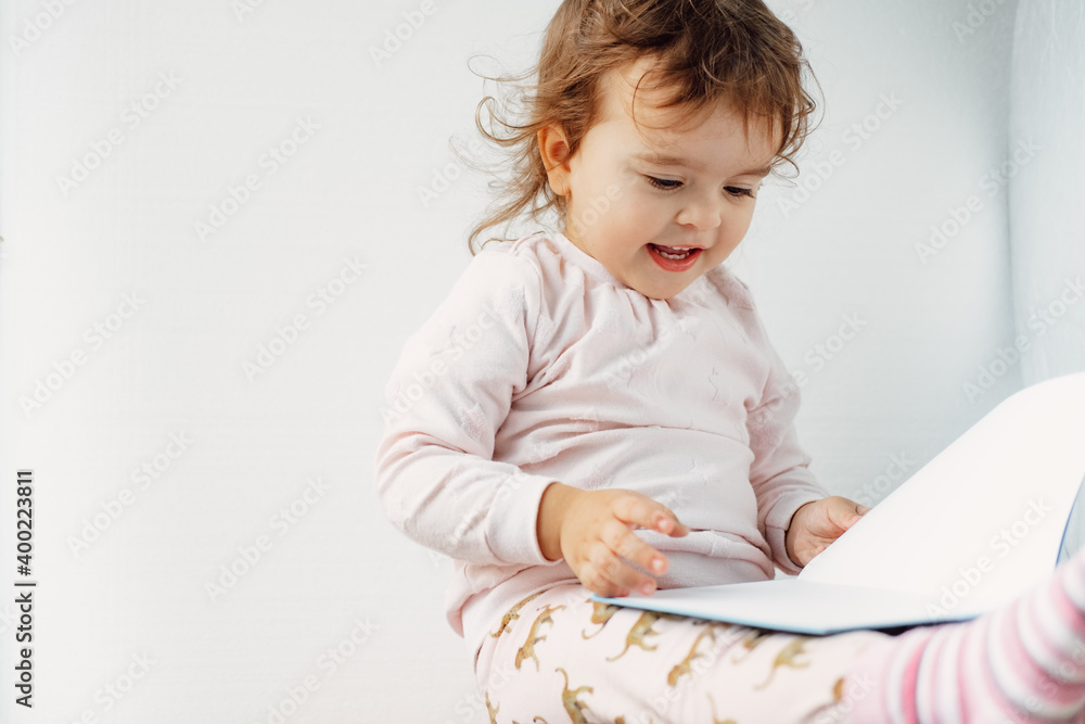 baby girl on a white background holding a book with pens, reading baby girl on a white background holding a book with pens, reading