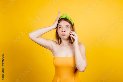 Foto tired girl italking on the phone, on a yellow background