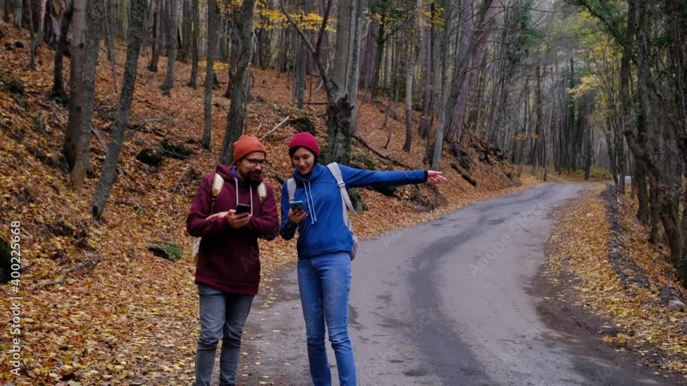 hipster hikers couple with backpacks got lost in forest, looking at travel smartphone application hipster hikers couple with backpacks got lost in forest, looking at travel smartphone application