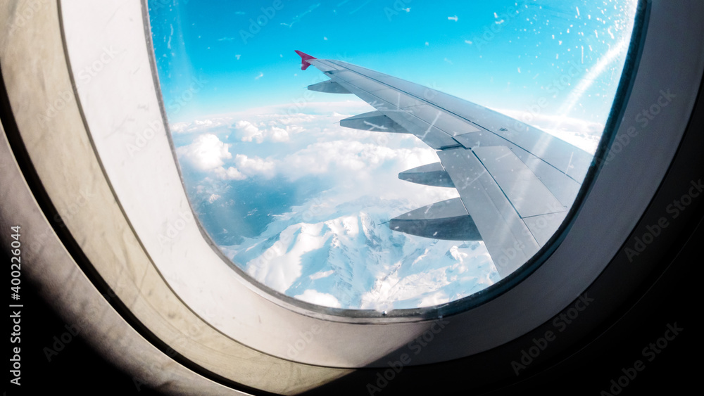 Aerial view of the snow capped mountains from the airplane porthole. Travel concept Aerial view of the snow capped mountains from the airplane porthole. Travel concept