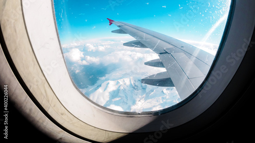 Aerial view of the snow capped mountains from the airplane porthole. Travel concept