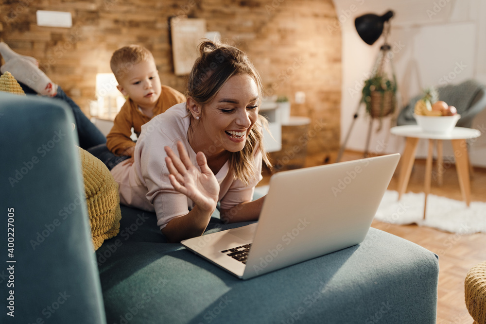 Happy single mother waving during video call over laptop at home.