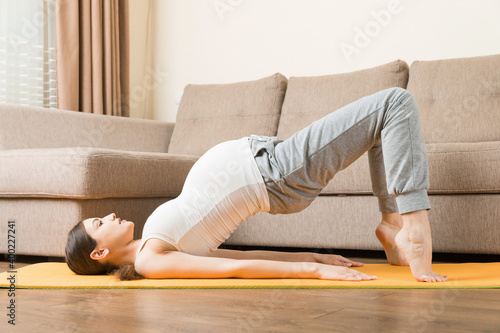 Pregnancy Yoga and Fitness concept at coronavirus time. Pregnant woman meditates indoor in yoga pose. Woman enjoying in meditation