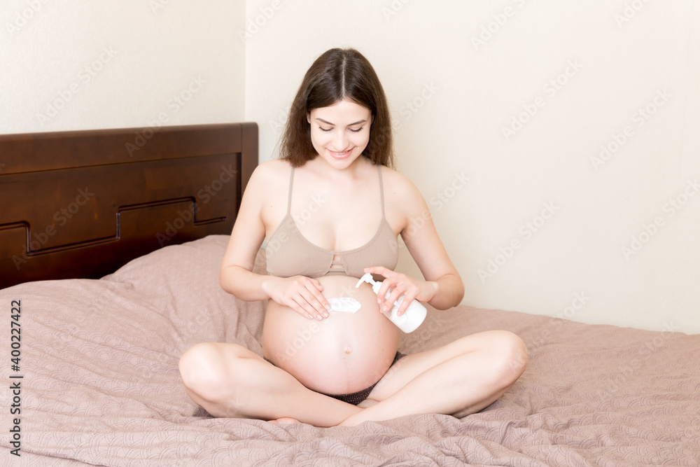 pregnant woman applying stretch mark cream to belly. pregnancy, people and maternity concept. pregnant apply anti-stretch mark cream on her belly pregnant woman applying stretch mark cream to belly. pregnancy, people and maternity concept. pregnant apply anti-stretch mark cream on her belly