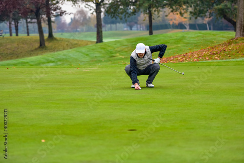 Golf player checking line for putting golf ball on green grass