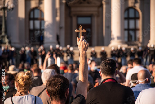 Orthodox believers protest in front of Assembly of the Republic of Serbia. A man in the crowd holds a wooden cross with inscription ''Jerusalem'' on it. Blurred background. Belgrade, Serbia 08.07.2020 © Dragan