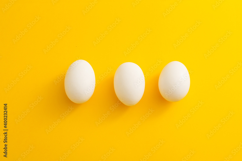 three white eggs on a yellow background three white eggs on a yellow background