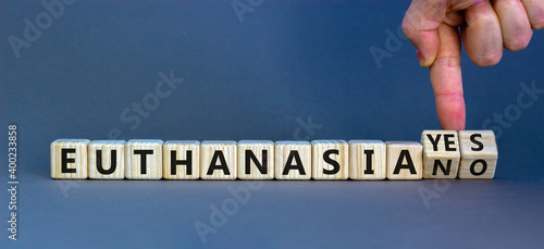 Euthanasia yes or no symbol. Male hand turns cubes and changes words 'Euthanasia yes' to 'Euthanasia no'. Medical and euthanasia yes or no concept. Beautiful grey background, copy space. photo