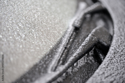 Shallow depth of field with detail of a frozen car windscreen and wipers after freezing rain phenomenon