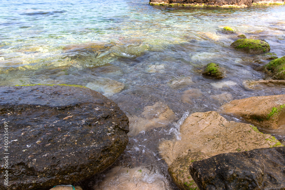 Rocks, mossy stones and sparkling sea water in the sea