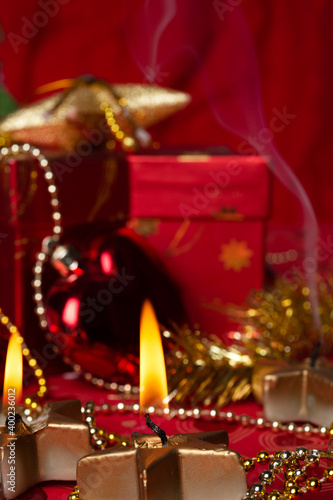 Christmas burning candles with decorations and  presents  at red background. Christmas holiday concept © anakondasp