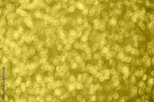 Golden abstract bokeh background. Color of the year 2021. Illuminating background. Christmas textures. Defocused shiny sequins.