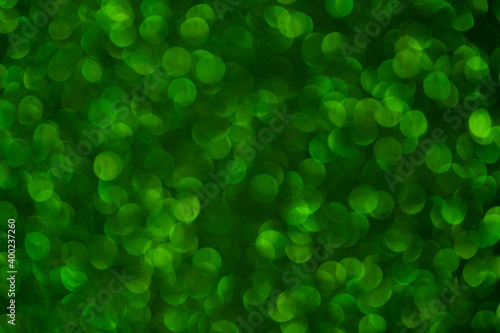 Green sparkling bokeh. Abstract texture. Festive and Christmas background. Defocused shiny sequins.