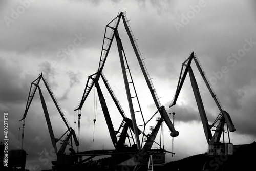 Crane's silhouettes over cloudy sky