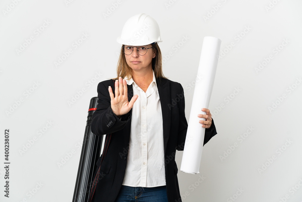 Middle age architect woman with helmet and holding blueprints over isolated background making stop gesture Middle age architect woman with helmet and holding blueprints over isolated background making stop gesture
