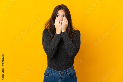 Teenager Brazilian girl isolated on yellow background nervous and scared putting hands to mouth