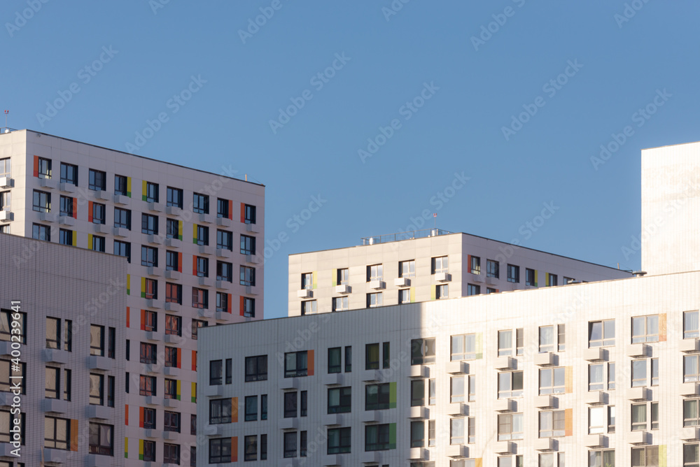 Solid facades of the houses. A city of only houses. Bright sun and high-rises.