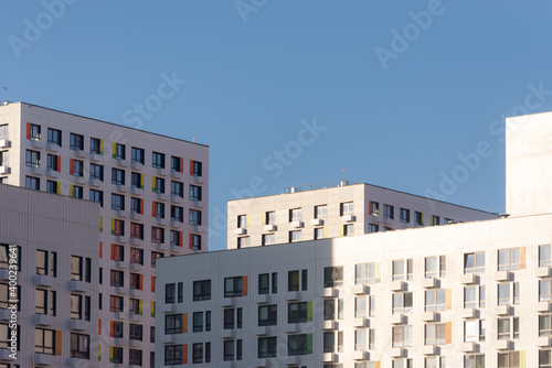 Solid facades of the houses. A city of only houses. Bright sun and high-rises.