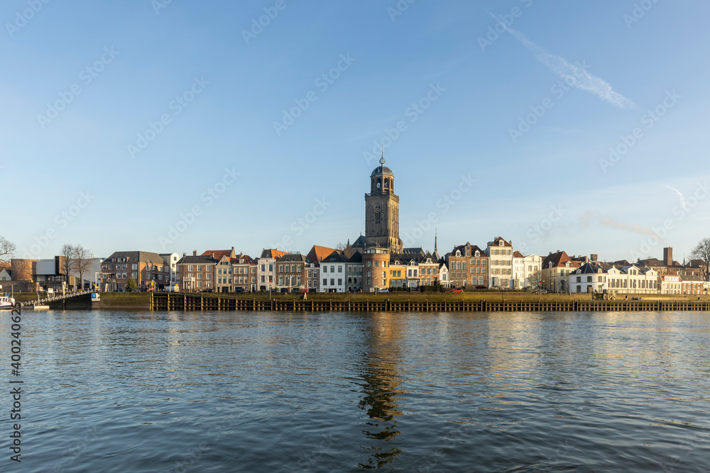 Mirroring cityscape panorama of the Dutch Hanseatic medieval city of Deventer in The Netherlands seen from the other side of the river IJssel at sunrise