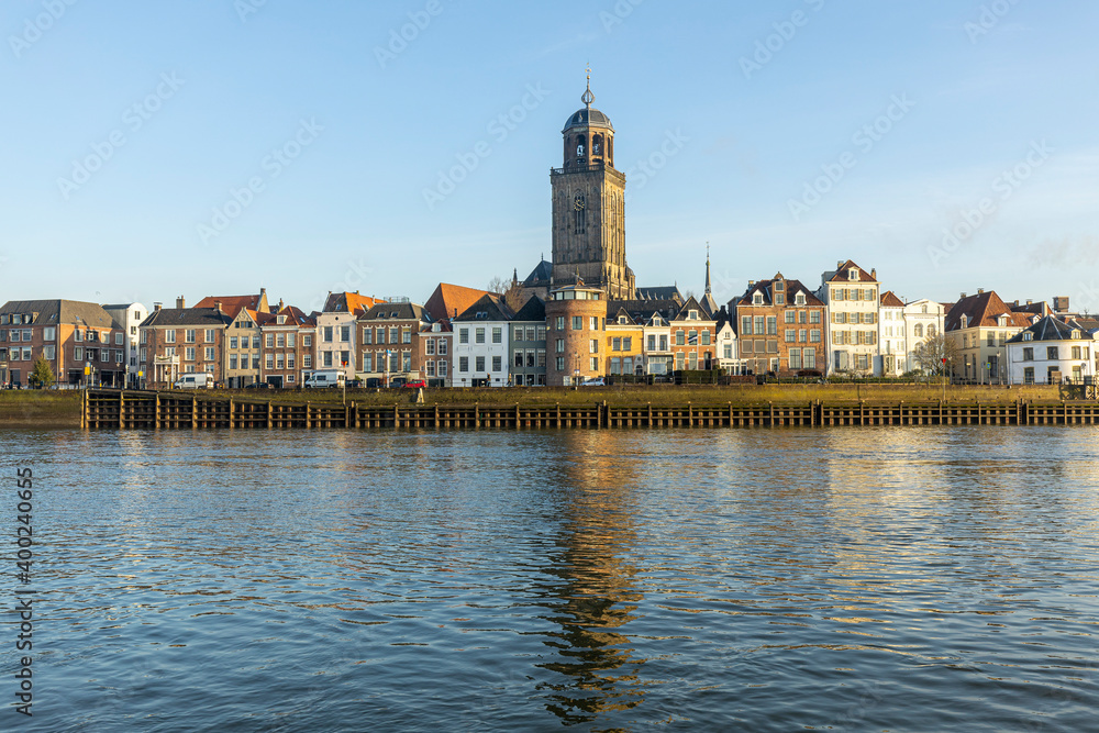 Stream and calm view of cityscape panorama of the Dutch Hanseatic medieval city of Deventer in The Netherlands seen from the other side of the river IJssel at sunrise