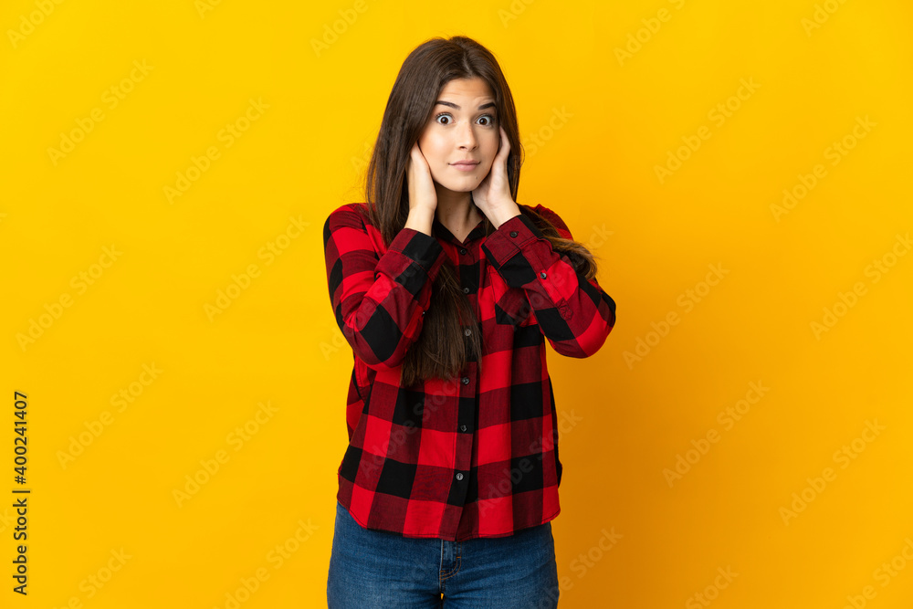 Teenager Brazilian girl isolated on yellow background frustrated and covering ears