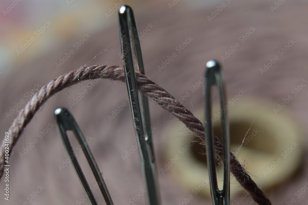 Three sewing needles are inserted into a spool of thread. close-up. Three sewing needles are inserted into a spool of thread. close-up.