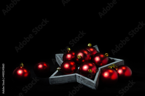 Still life of red christmas tree balls and a wooden star with black background