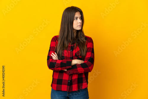 Teenager Brazilian girl isolated on yellow background keeping the arms crossed © luismolinero