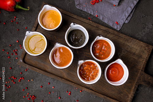 assorted sauces on beautiful board, on black concrete table top view photo