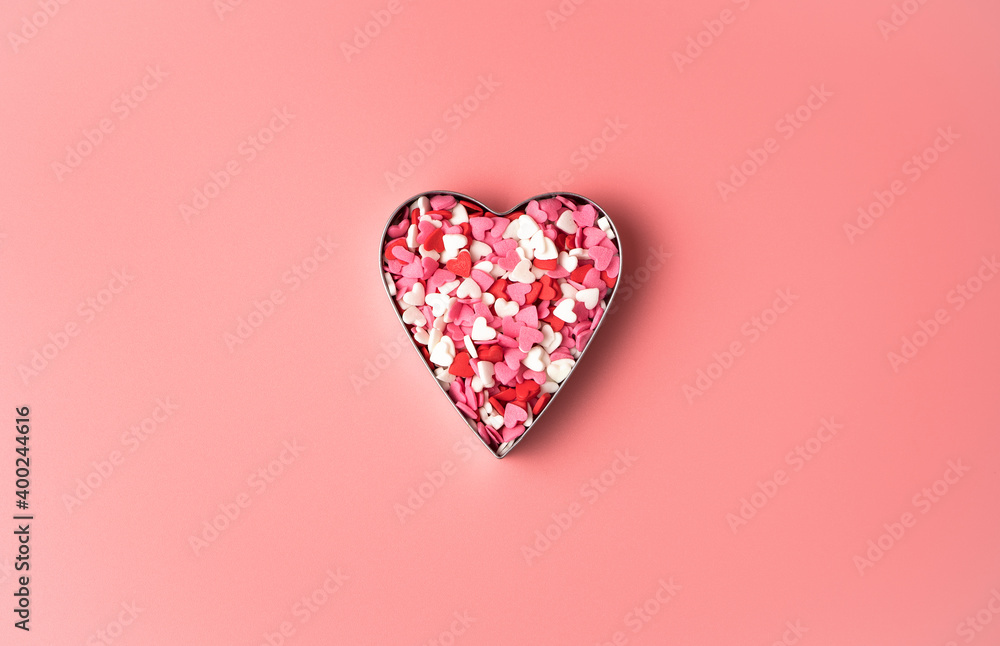 Heart of small candies in the shape of hearts on a pink background. Top view with copy space. Concept of February 14, love.