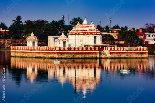 Bindu Sagar or Bindu Sarovar, a Temple Tank in Bhubaneswar, Odisha, India, with an ancient Hindu Shrine in the center reflected in the clear blue water.