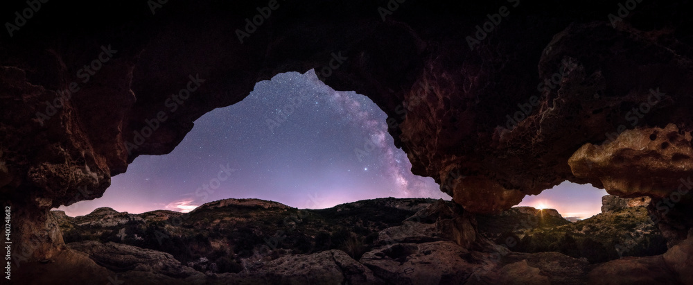 Night panoramic inside a megalithic monument, with engravings and geoglyphs carved in the rock. Observing the milky way and the moon from inside the Neolithic arch.