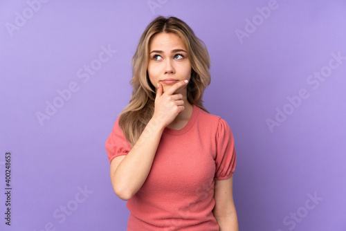 Teenager Russian girl isolated on purple background having doubts and with confuse face expression