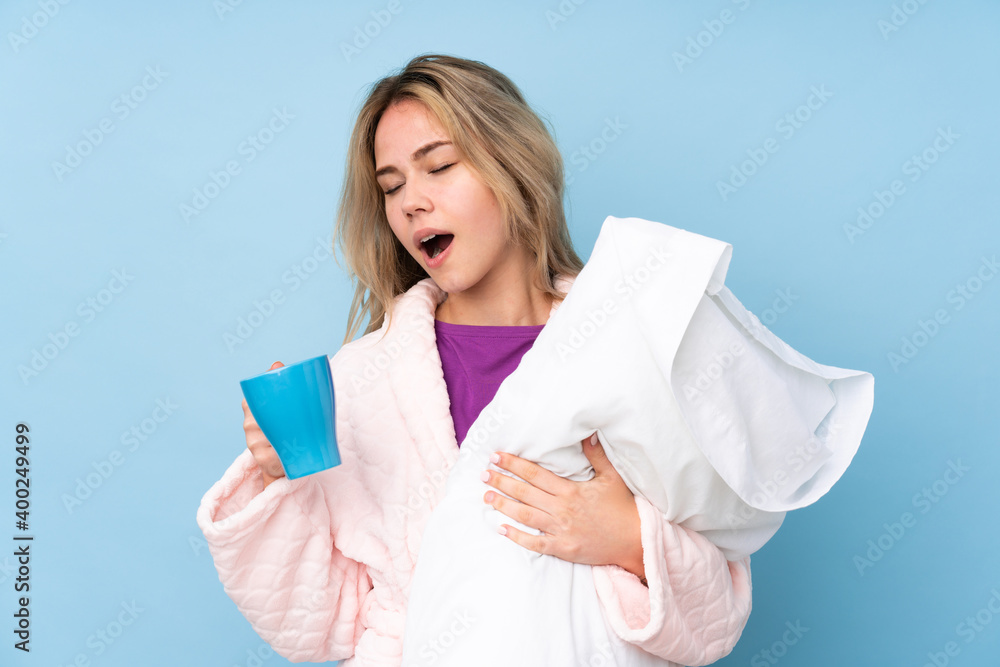 Fototapeta premium Teenager Russian girl in pajamas isolated on blue background