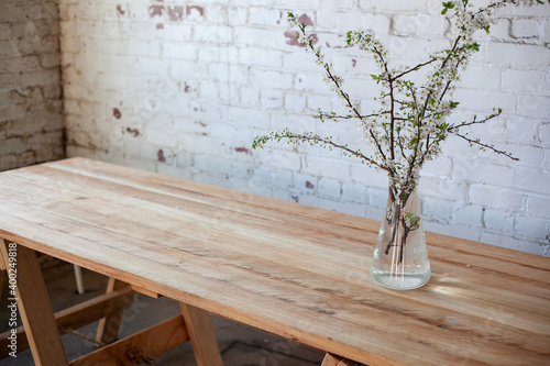 flowering branches of a cherry tree in a glass vase on a wooden table in the interior