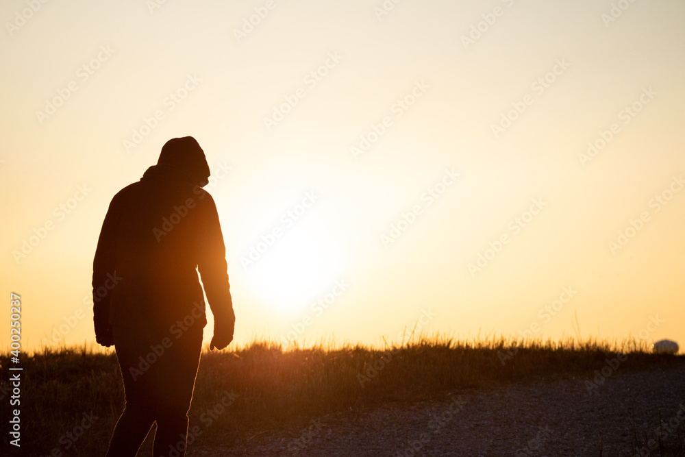 Silhouette walking toward sunset
