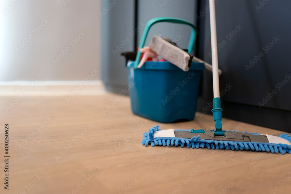 Fototapeta premium Cleaning concept. Mop and plastic bucket with cleaning products on the floor