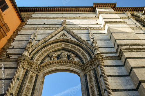 Low-angle view of the marble ogival portal  1345  opened on the staircase that connect the Cathedral  approx. 1220-1370  with the Baptistery of St John  1316-1325   Siena  Tuscany  Italy