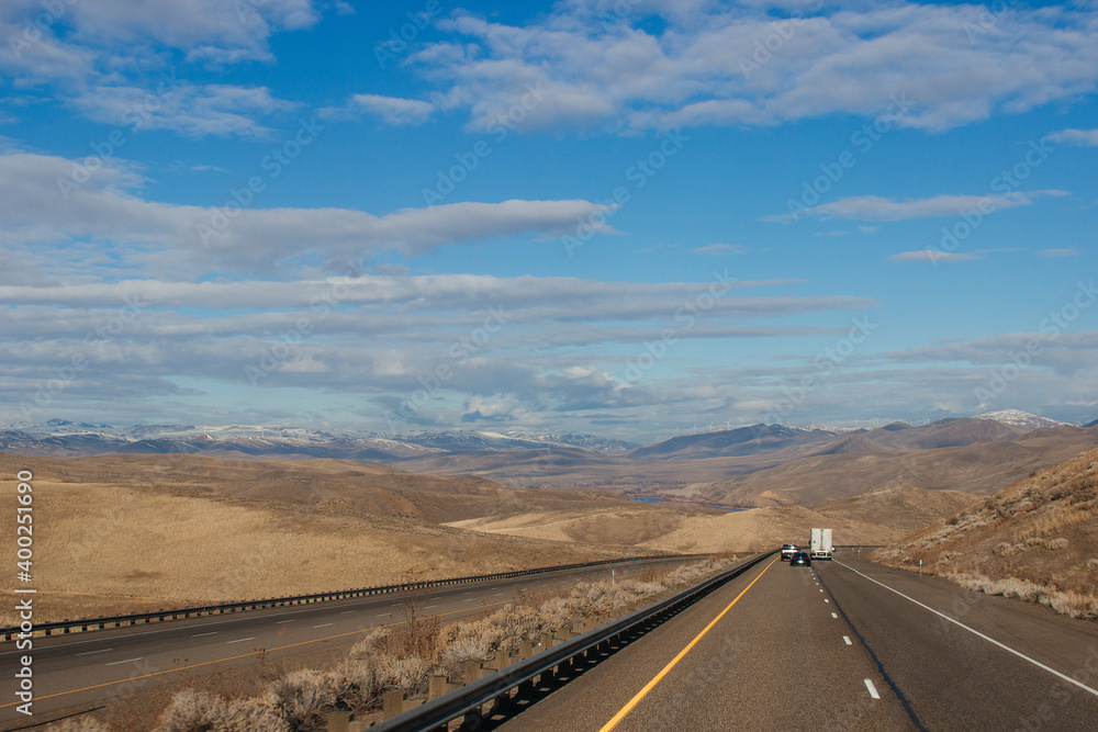 A picturesque highway along which cars and trucks drive among the mountains, slightly covered with snow, on a bright sunny autumn day. Oregon Scenic Hwy, OR, USA, 12-15-2019