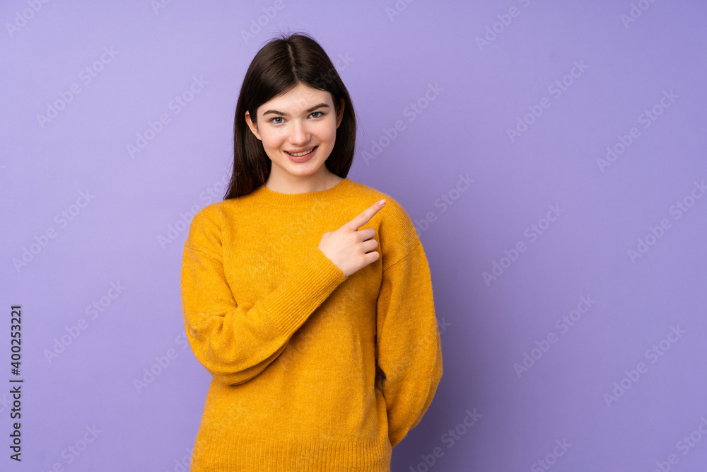 Fototapeta premium Young Ukrainian teenager girl over isolated purple background pointing to the side to present a product