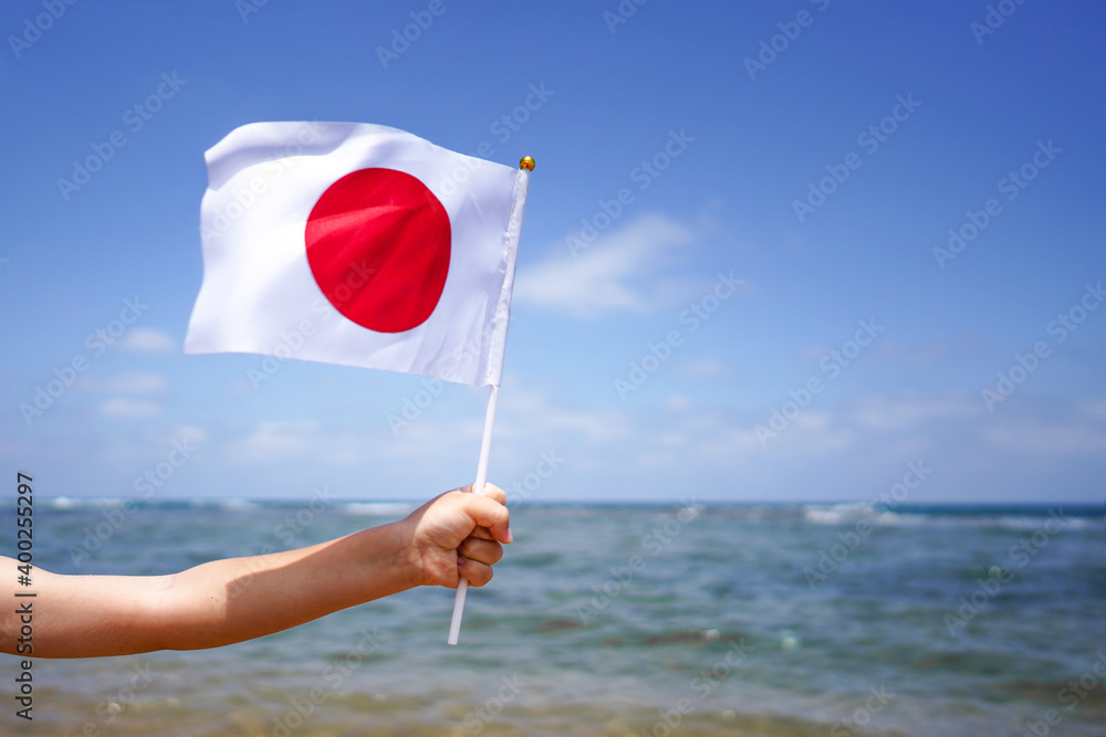 Hands of kid girl holding Japan flag against the sea horizon. Independence Day concept. Hands of kid girl holding Japan flag against the sea horizon. Independence Day concept.