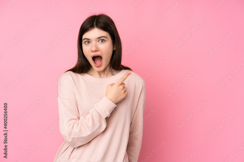 Young Ukrainian teenager girl over isolated pink background surprised and pointing side Young Ukrainian teenager girl over isolated pink background surprised and pointing side