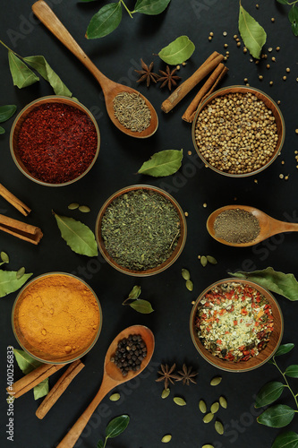 Fototapeta Wide variety spices and herbs on background of black table