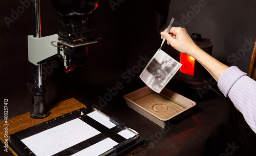 Analog photo printing. The photographer prints a black and white photograph. Photolaboratory. Red light photo