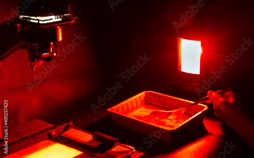 Analog photo printing. The photographer prints a black and white photograph. Photolaboratory. Red light