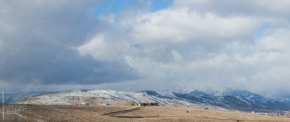 Beautiful winter landscape - snow-capped mountains, small cozy houses, blue sky with fluffy clouds on a sunny day are visible in the distance