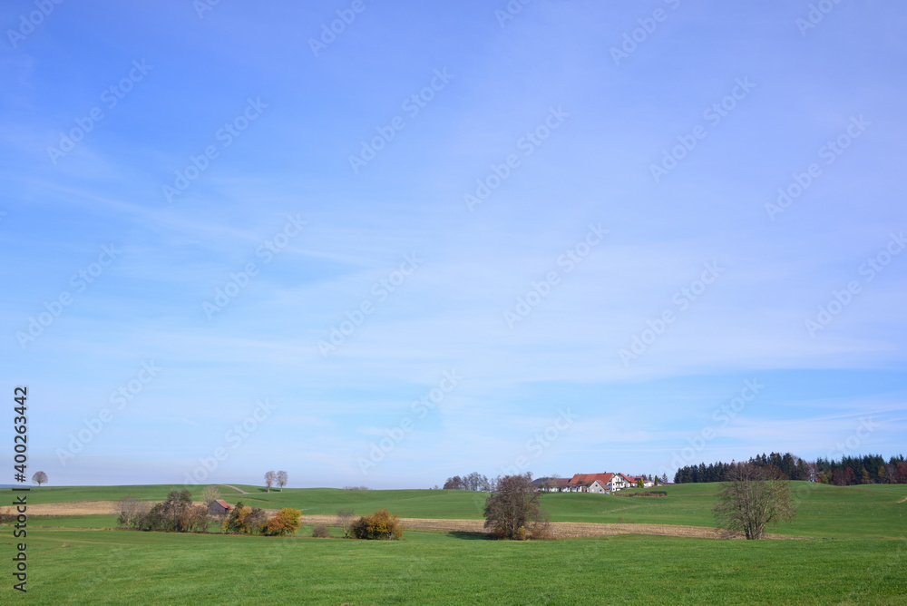 Wide landscape in southern Germany with a deserted farm in nature against a blue sky with clouds and space for text