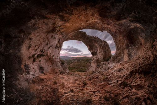 Sunset in the cave. Panoramic view of the interior of a cavern  at the entrance an arch crosses the top. Interior of the Cueva de los Arcos. Sunset in a large cave  with an arch at the entrance.  