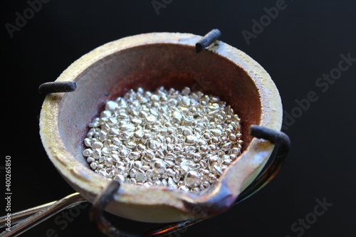 A ceramic crucible or melting pot with grains of sterling silver 925 for jewelry making after hand smelting in a workshop. One of the two major precious metals on the market.